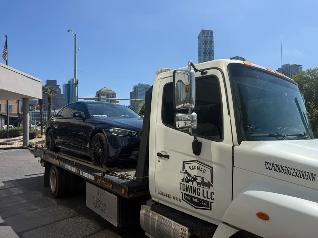 Sarmad Towing LLC flatbed tow truck loaded with a dark sedan in Kyle, Texas